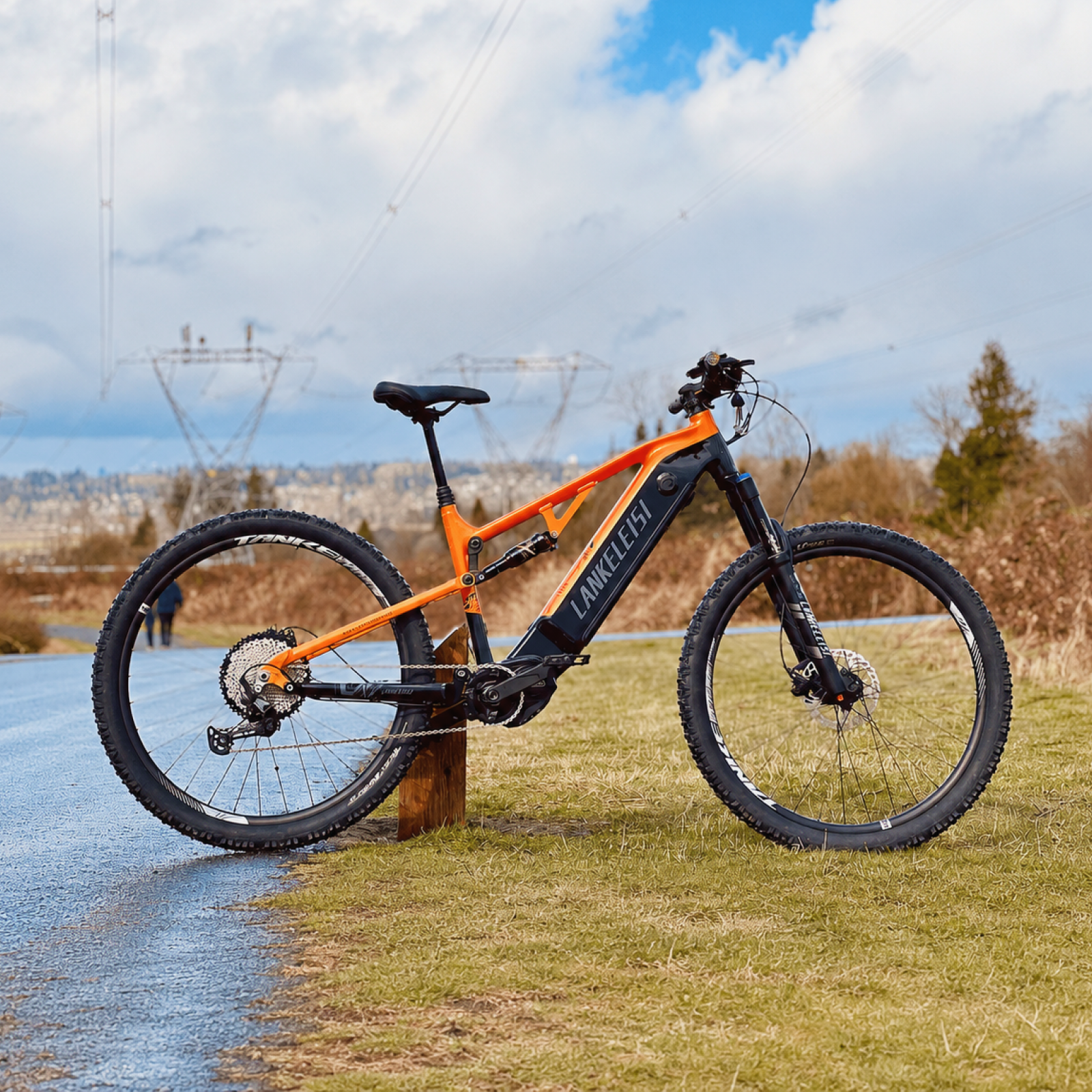 Lankeleisi GT800 E-Bike auf einer grasbewachsenen Landschaft, detailreiche Ansicht des schwarzen Fahrrads mit Akku und Rahmen.